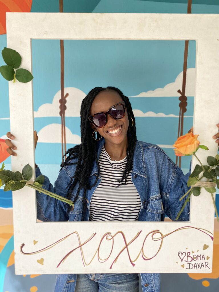 black woman holding a photo square that says XOXO
