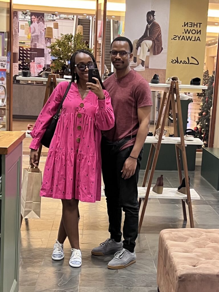 black couple take a selfie in front of a store mirror