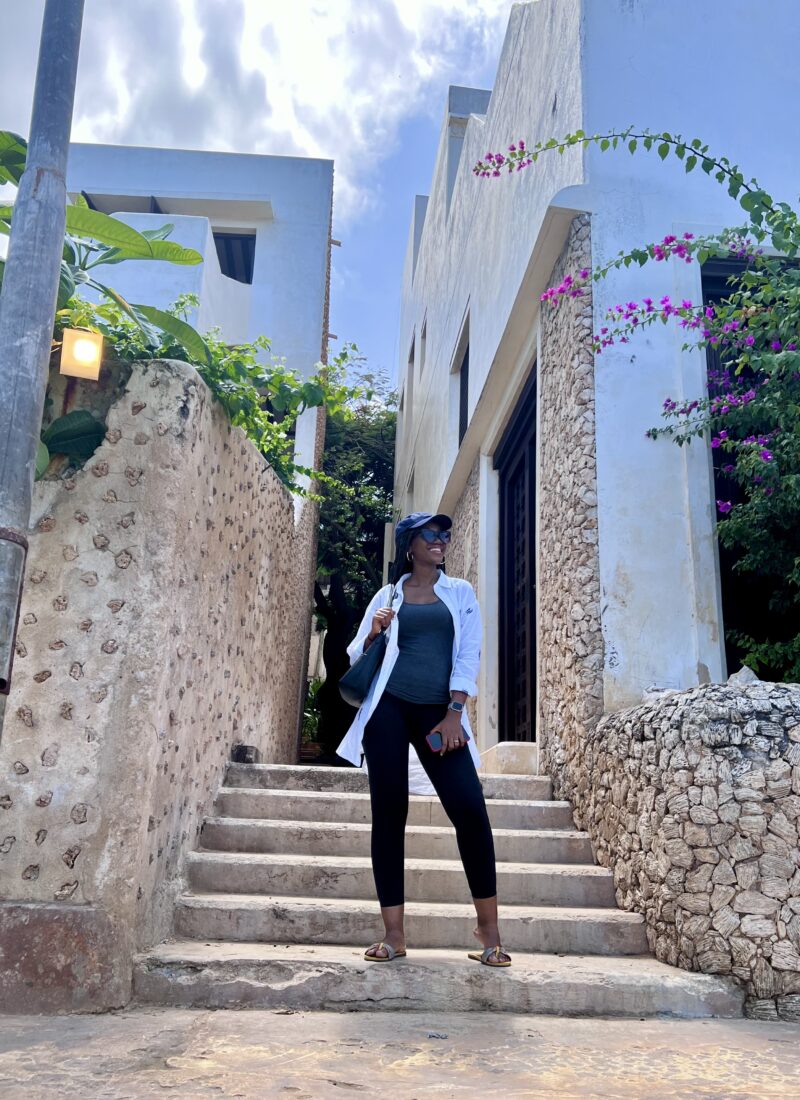 black woman stands in front of stairs in shela, lamu