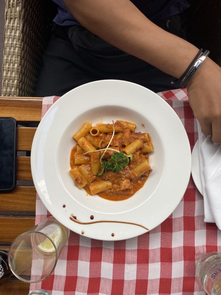a plate of rigatoni at lucca's nairobi sits on a red gingham table cloth